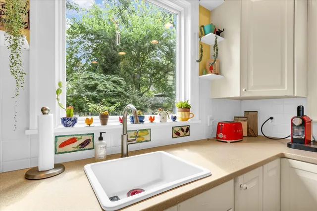 a kitchen with a sink and white cabinets with wooden floor