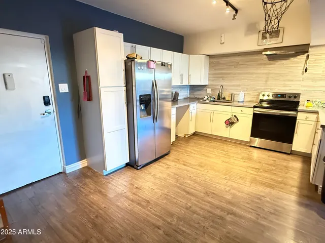 a kitchen with stainless steel appliances a refrigerator and wooden floor