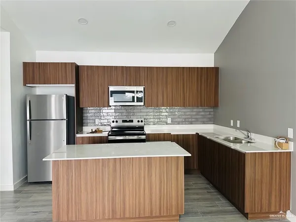 a kitchen with stainless steel appliances a refrigerator a sink a stove a microwave and wooden cabinets