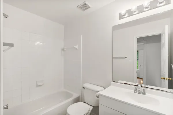 a bathroom with a bathtub shower sink mirror vanity and toilet