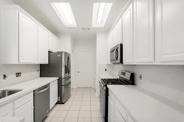 a kitchen with stainless steel appliances a refrigerator sink and white cabinets