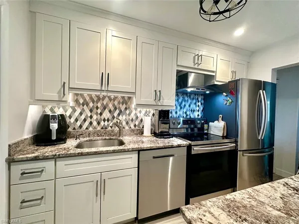 a kitchen with stainless steel appliances kitchen island granite countertop a refrigerator and a stove top oven