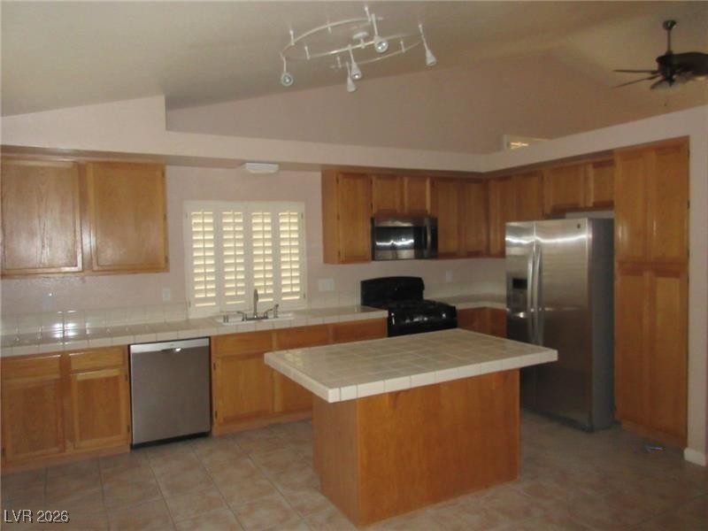 171 Enloe Street Henderson, NV 89074 - Photo 3 of 12 Kitchen featuring appliances with stainless steel finishes, lofted ceiling, tile countertops, light tile patterned floors, and brown cabinetry
