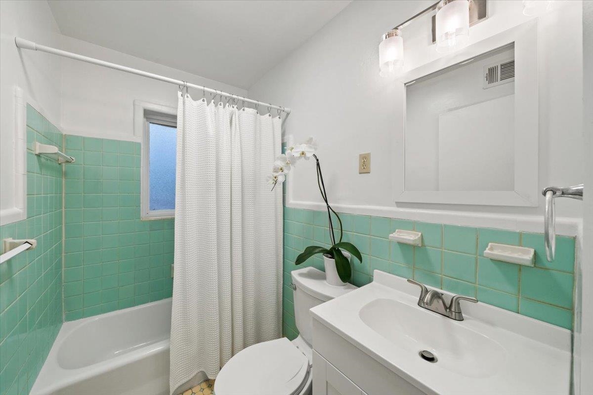 1554 Hopewell Road Memphis, TN 38117 - Photo 9 of 24 Bathroom with vanity, shower / bath combo with shower curtain, wainscoting, and tile walls