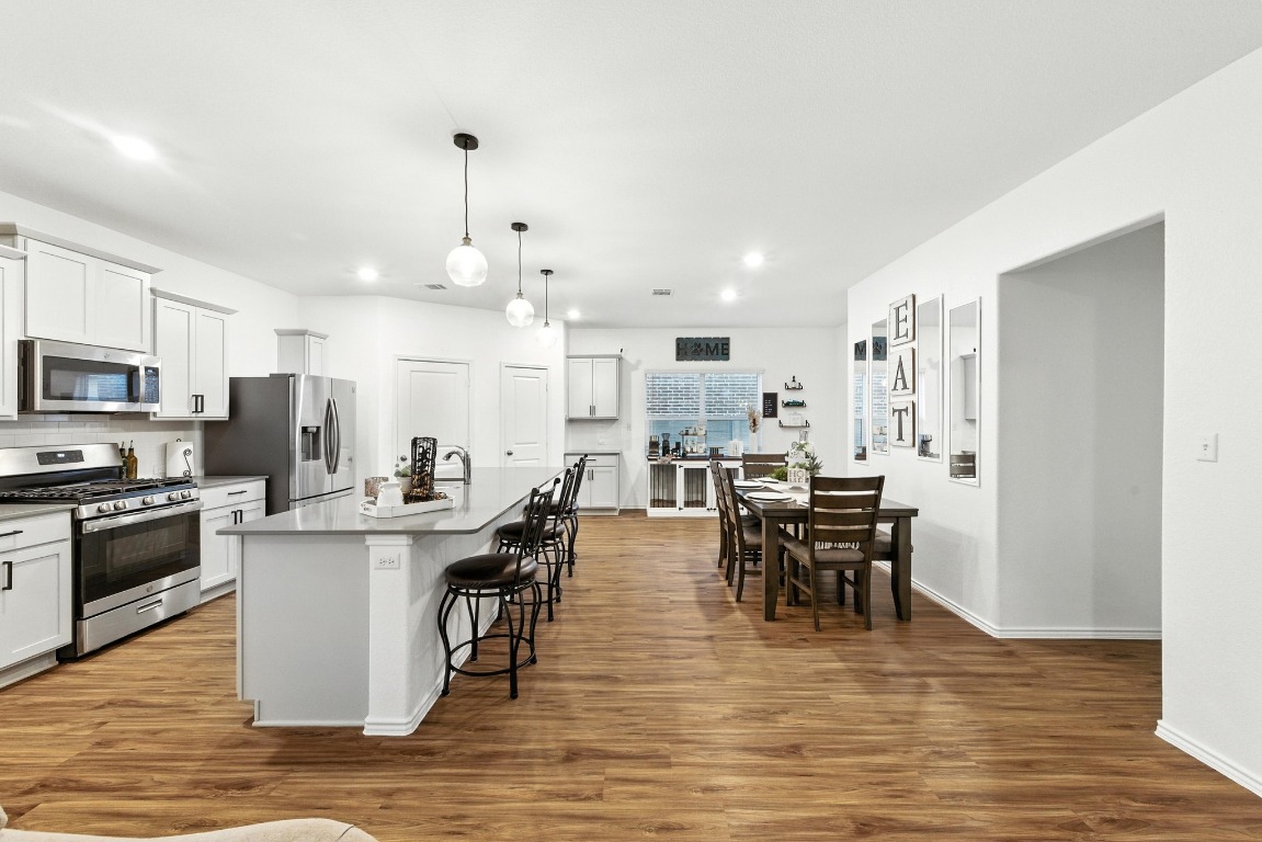 112 Cherry Ridge Road Georgetown, TX 78628 - Photo 10 of 35 Kitchen featuring appliances with stainless steel finishes, a center island with sink, dark wood-type flooring, pendant lighting, and recessed lighting