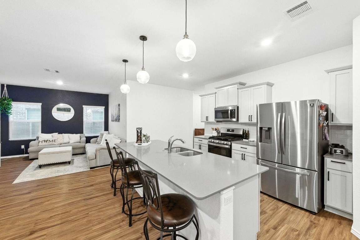 112 Cherry Ridge Road Georgetown, TX 78628 - Photo 12 of 35 a kitchen with a refrigerator a stove top oven a sink dishwasher and white cabinets with wooden floor
