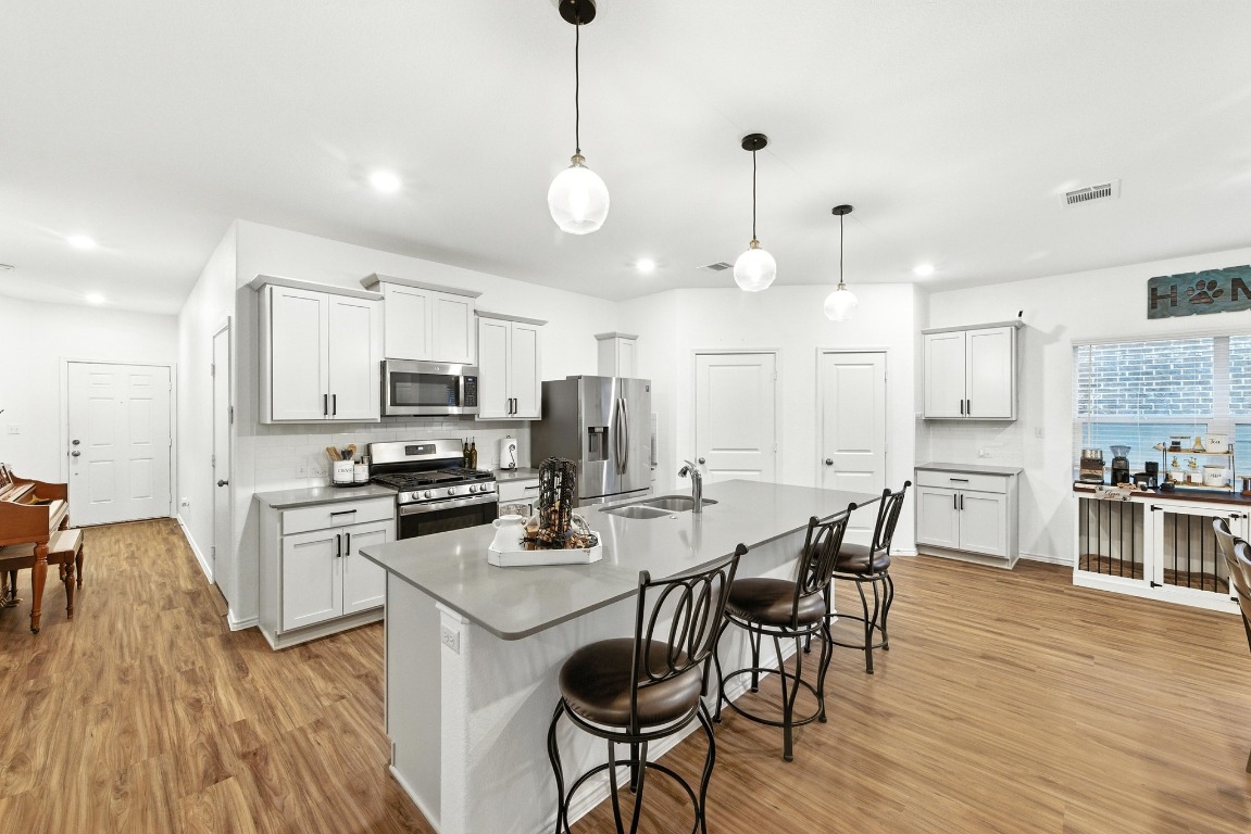112 Cherry Ridge Road Georgetown, TX 78628 - Photo 13 of 35 a kitchen with stainless steel appliances kitchen island granite countertop a stove a refrigerator a kitchen island a dining table and chairs with wooden floor