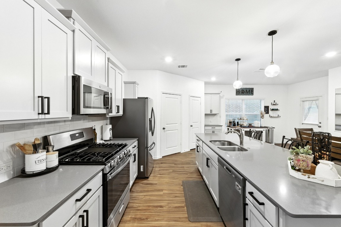 112 Cherry Ridge Road Georgetown, TX 78628 - Photo 14 of 35 Kitchen with stainless steel appliances, a center island with sink, white cabinets, decorative backsplash, and pendant lighting