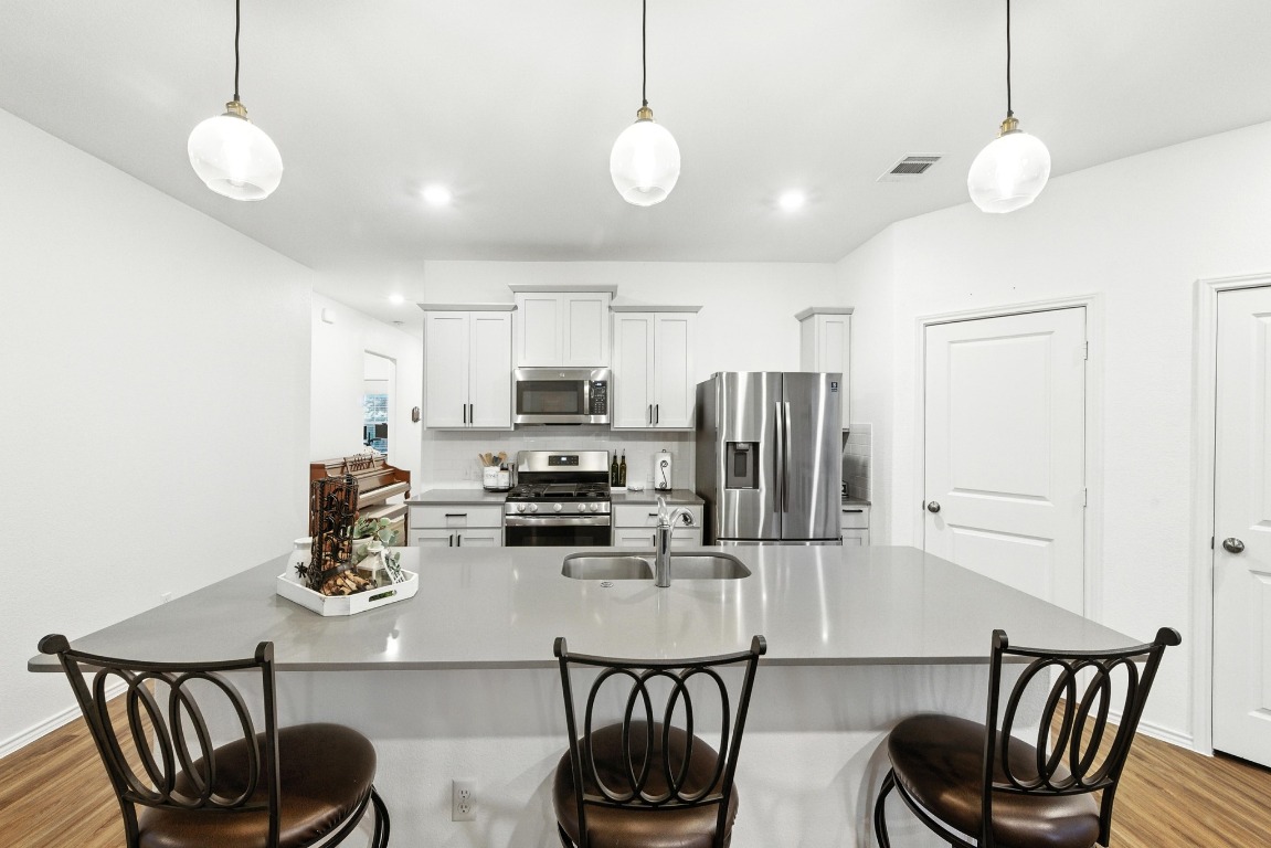 112 Cherry Ridge Road Georgetown, TX 78628 - Photo 17 of 35 a kitchen with stainless steel appliances kitchen island granite countertop a table chairs and a refrigerator