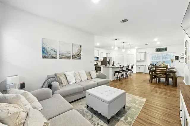 a kitchen with a refrigerator a stove top oven a sink dishwasher and white cabinets with wooden floor