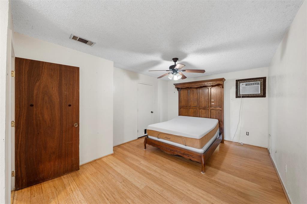 413 Texas Avenue Hewitt, TX 76643 - Photo 19 of 26 Bedroom with light wood finished floors, a textured ceiling, a wall mounted AC, and a ceiling fan