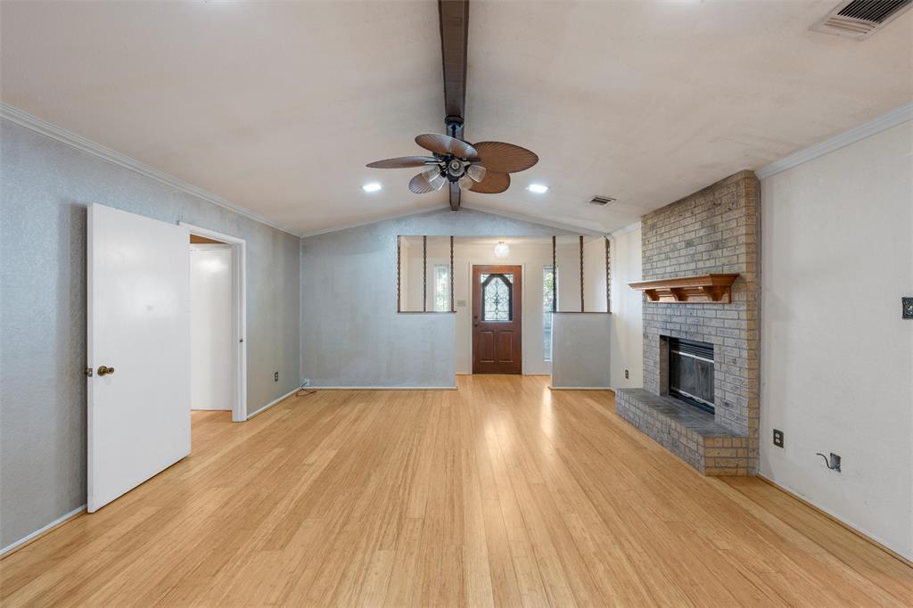413 Texas Avenue Hewitt, TX 76643 - Photo 5 of 26 Unfurnished living room featuring light wood-style flooring, a ceiling fan, a fireplace, and crown molding