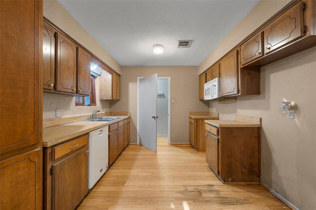 413 Texas Avenue Hewitt, TX 76643 - Photo 8 of 26 Kitchen featuring white appliances, light wood-style floors, light countertops, and brown cabinetry