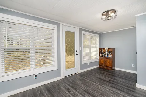 a view of an empty room with window and wooden floor