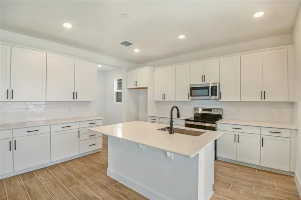 a kitchen with kitchen island sink stove and cabinets