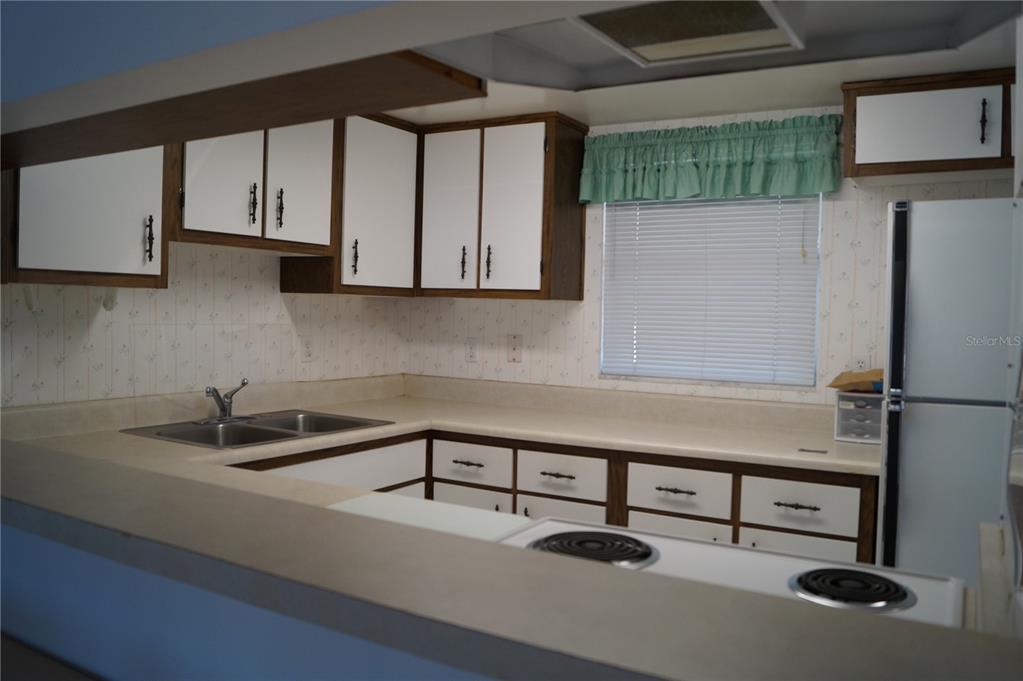7701 Starkey Road, Unit 408 Seminole, FL 33777 - Photo 15 of 28 a kitchen with a sink a refrigerator and cabinets