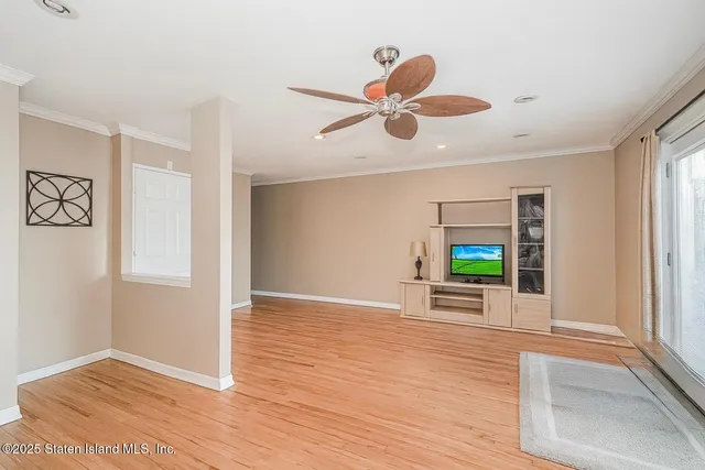 a view of an empty room with window and wooden floor