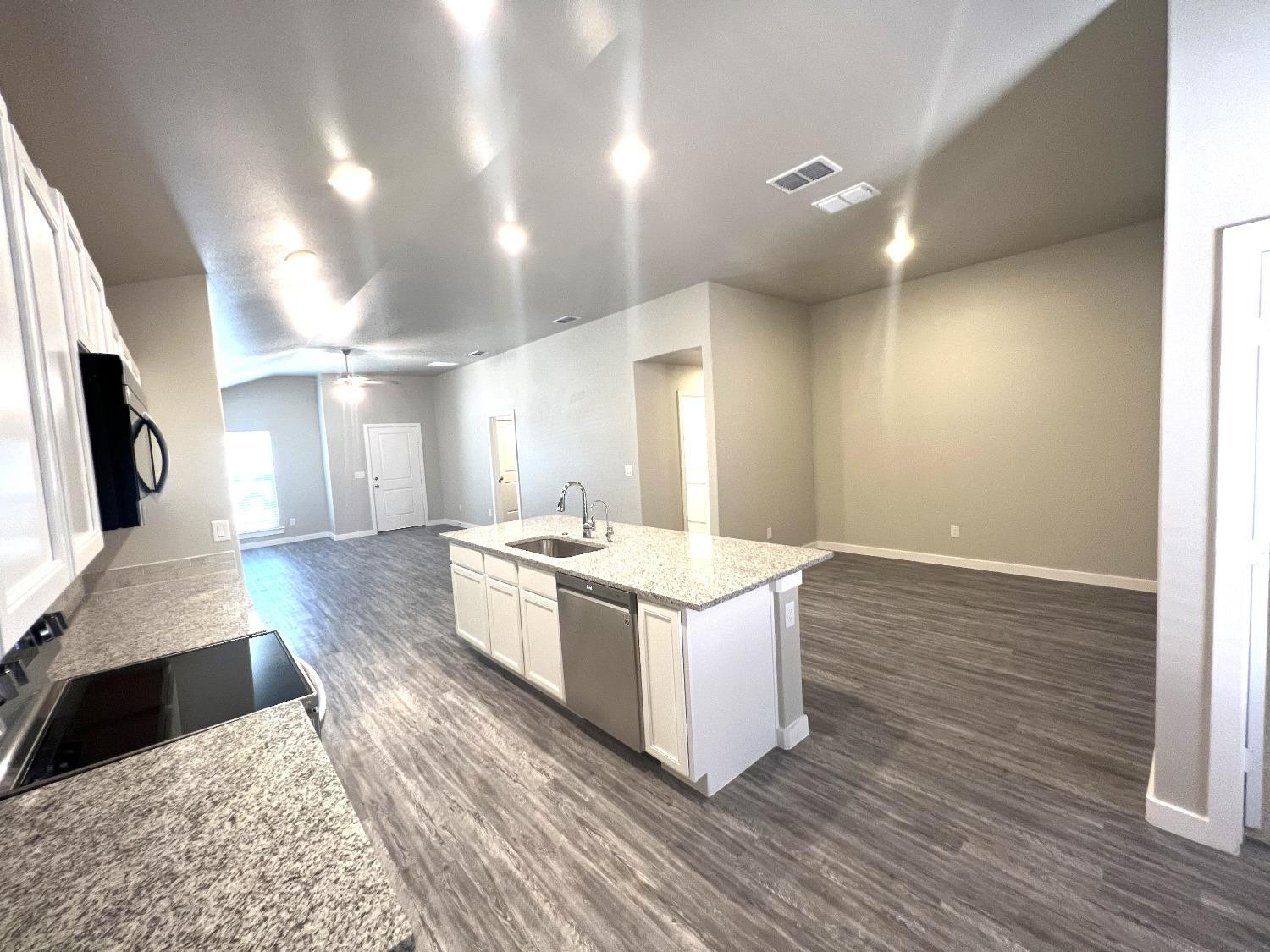 13705 Avenue Q Lubbock, TX 79423 - Photo 5 of 13 a large white kitchen with wooden floor and stainless steel appliances