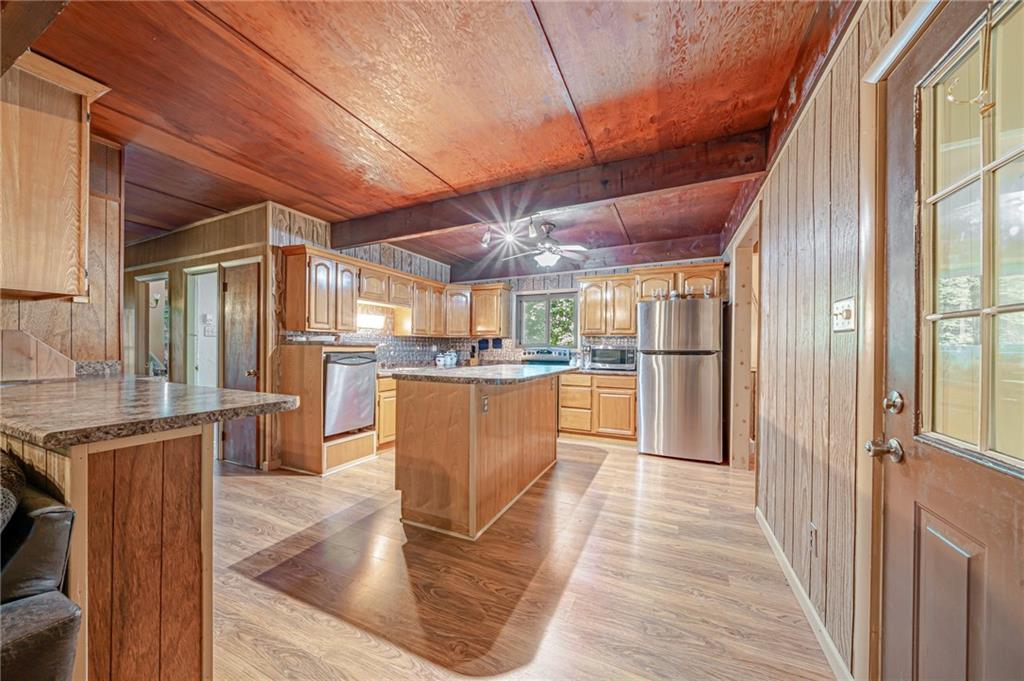 218 Horse Shoe Bend Road Acme, PA 15610 - Photo 3 of 31 a kitchen with stainless steel appliances granite countertop a refrigerator a sink dishwasher a stove and a dining table with wooden floor