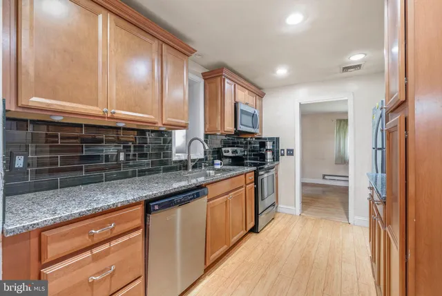 a kitchen with stainless steel appliances granite countertop a sink and wooden cabinets