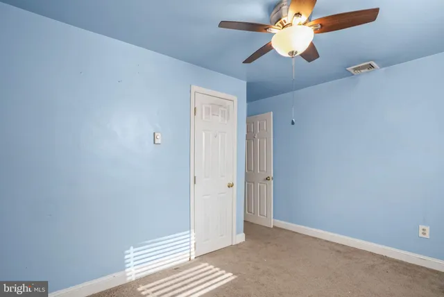 an empty room with closet and a chandelier fan