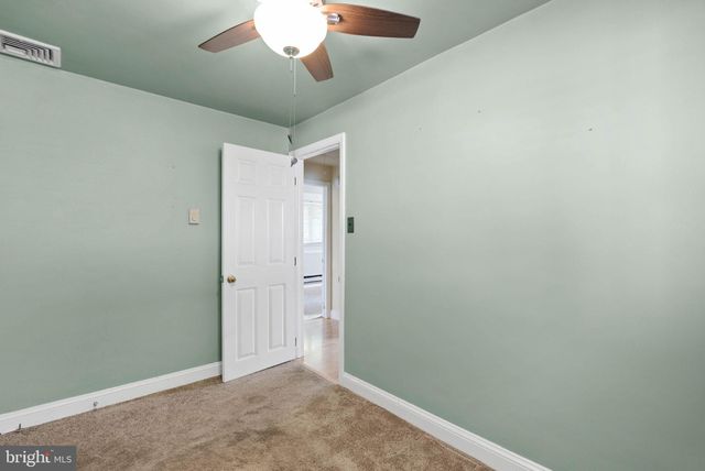 an empty room with a fan & a ceiling fan
