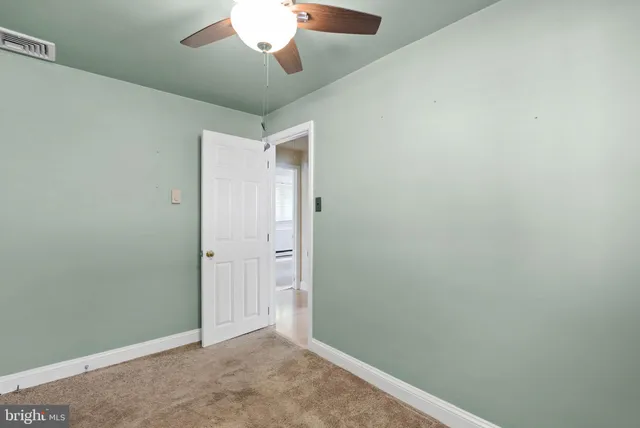 an empty room with a fan & a ceiling fan