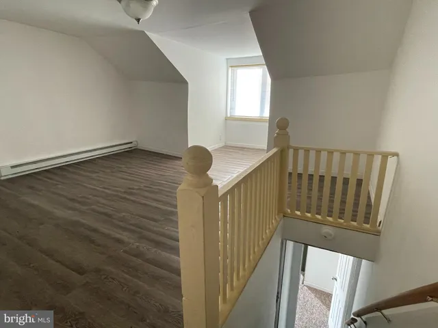a view of a hallway with wooden floor and staircase