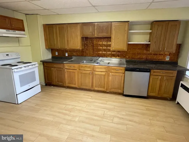 a kitchen with granite countertop a sink a stove and cabinets