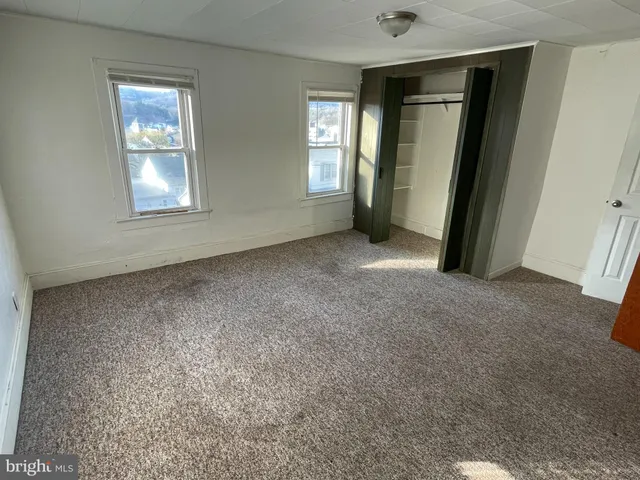an empty room with windows and closet