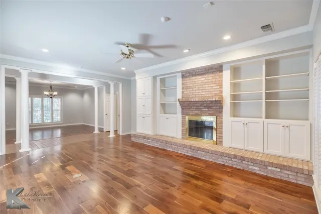 a view of a livingroom with wooden floor a ceiling fan and windows