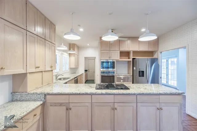 a kitchen with stainless steel appliances granite countertop a sink a stove counter space and cabinets