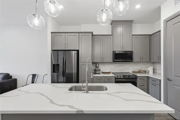 a kitchen with stainless steel appliances kitchen island granite countertop a refrigerator a stove a sink dishwasher and a microwave with wooden floor