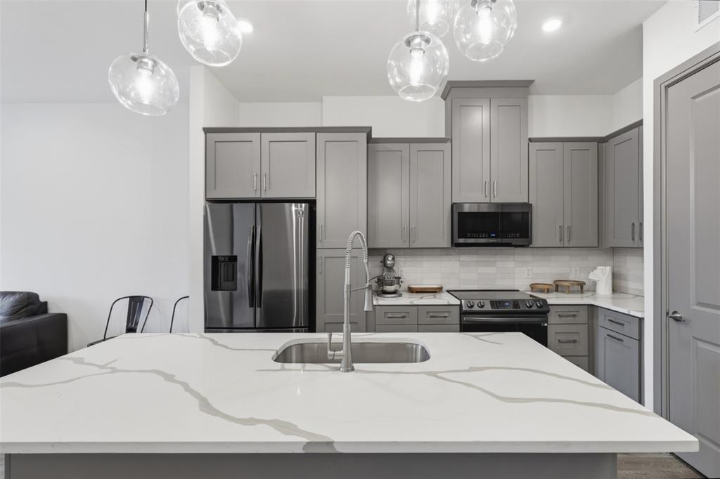 2700 Old Denton Road, Unit 2272 Carrollton, TX 75007 - Photo 2 of 40 a kitchen with stainless steel appliances kitchen island granite countertop a refrigerator a stove a sink dishwasher and a microwave with wooden floor