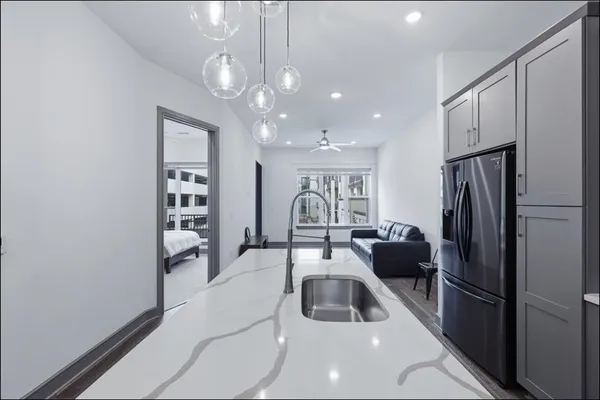 a kitchen with a refrigerator a sink dishwasher a dining table and chairs with wooden floor