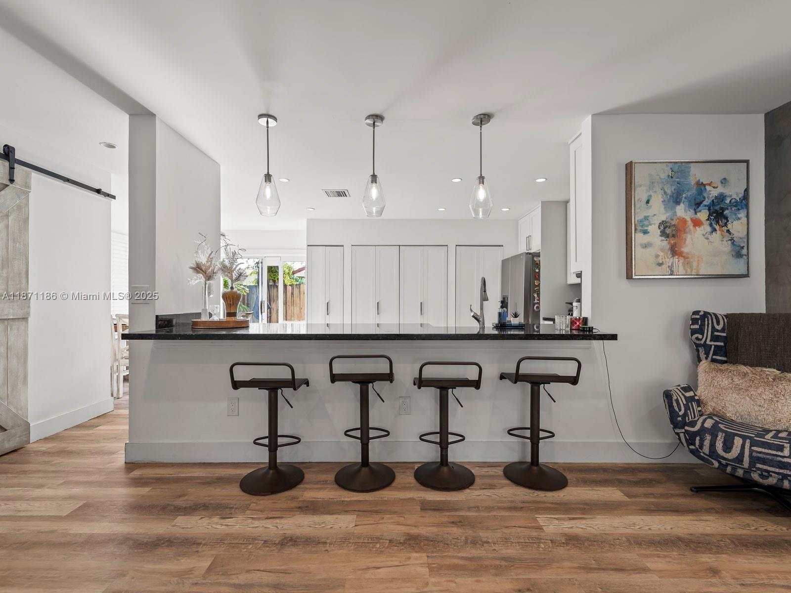 15293 Southwest 111th Street Miami, FL 33196 - Photo 16 of 32 a kitchen with stainless steel appliances granite countertop a table chairs in it and wooden floors