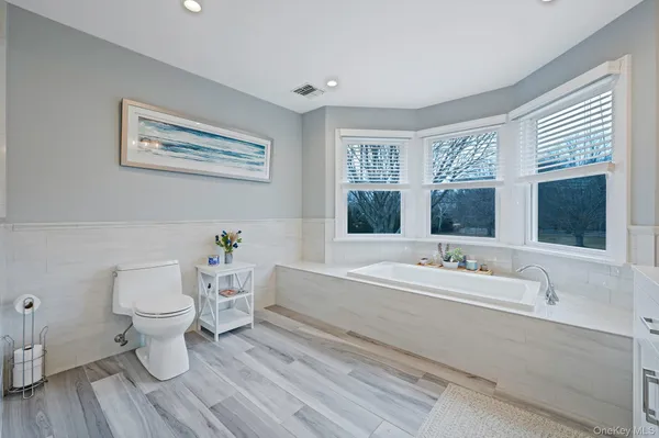 a bathroom with a toilet a sink and wooden floor