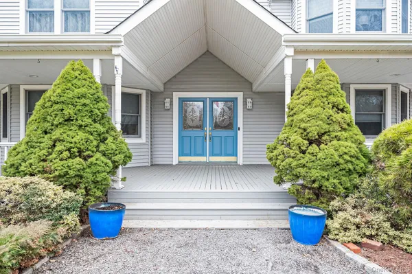 a view of a house with potted plants and a bench