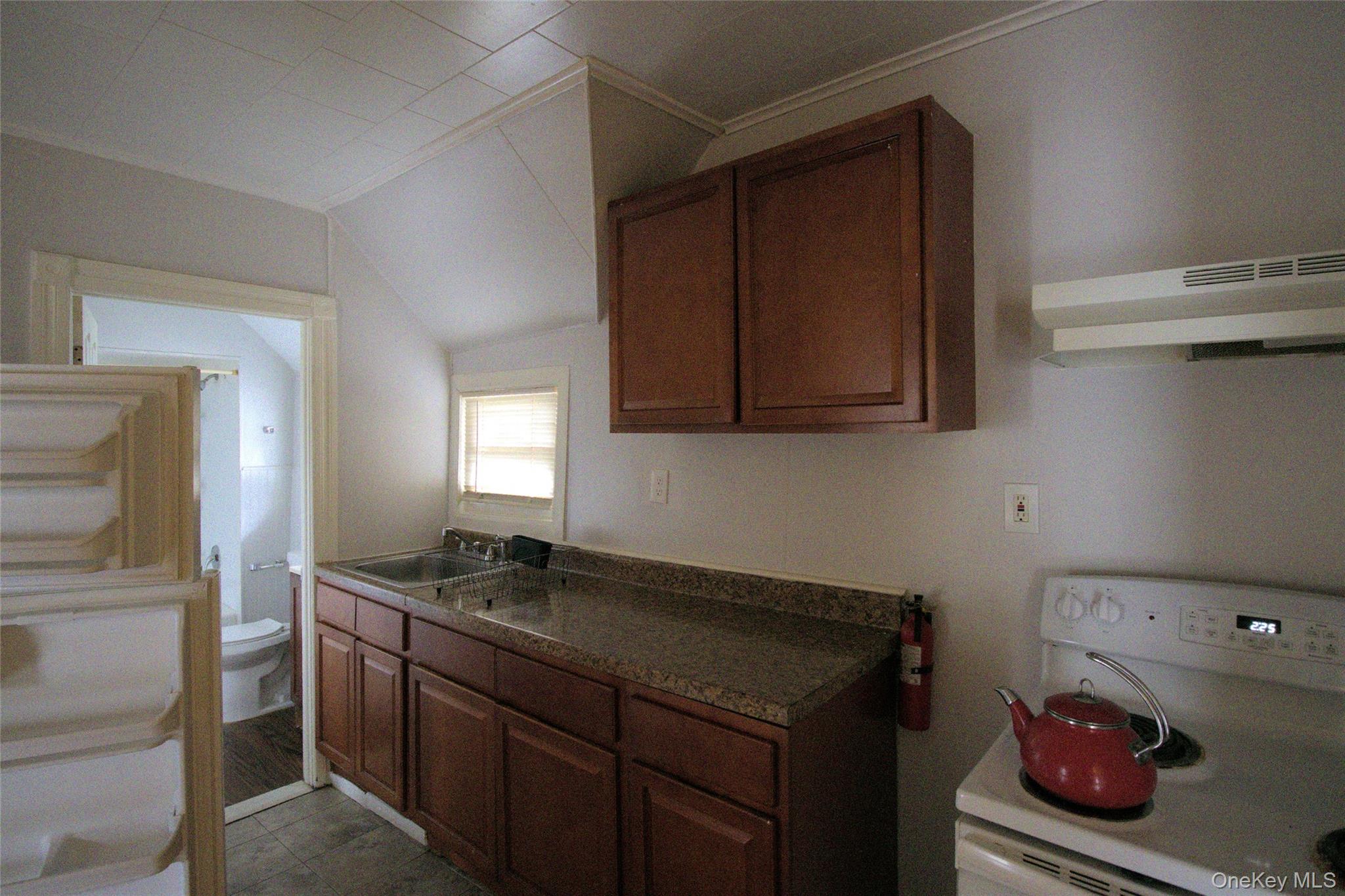 9 Spring Street Liberty, NY 12754 - Photo 16 of 29 Kitchen area featuring wood-finish cabinetry, a double basin stainless steel sink, and speckled countertops