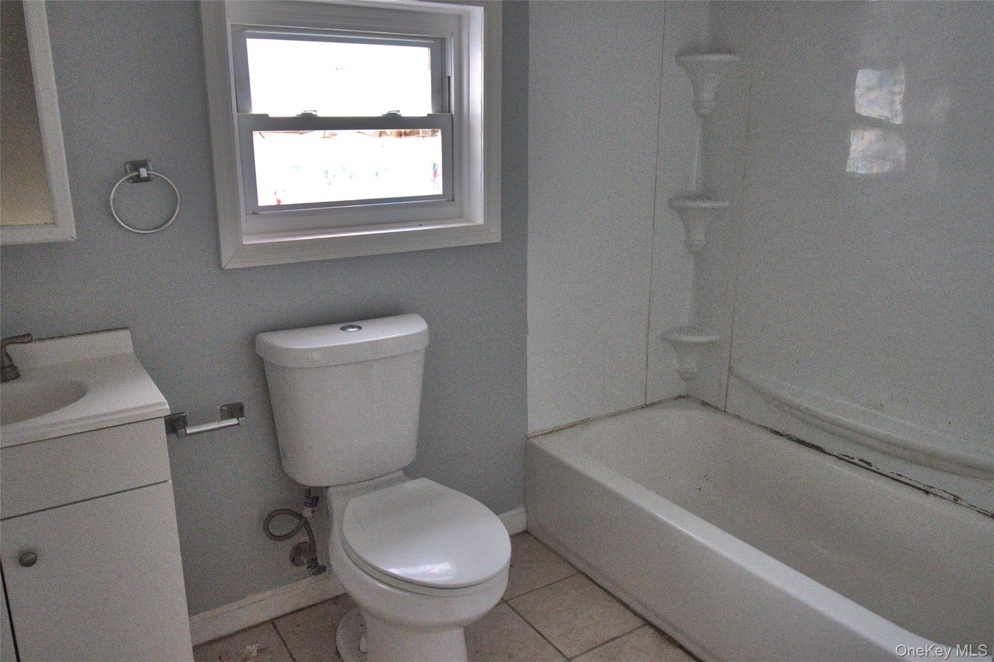 9 Spring Street Liberty, NY 12754 - Photo 19 of 29 Bathroom featuring a window, white vanity with integrated sink, toilet, and a white tub with integrated corner shelving