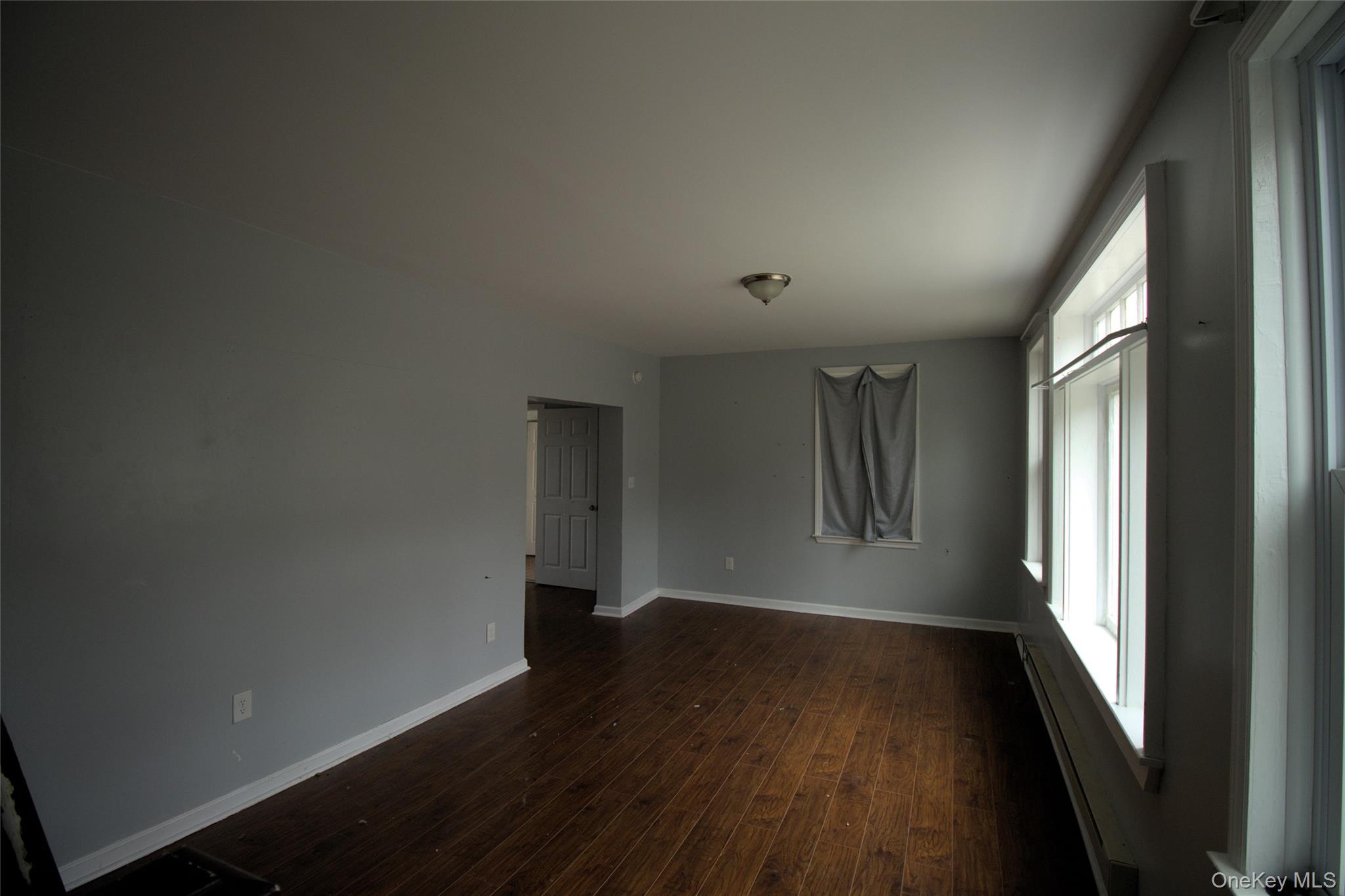 9 Spring Street Liberty, NY 12754 - Photo 21 of 29 Spacious interior featuring wood-finish flooring, light gray wall color, multiple large windows, white trim, and a semi-flush mount ceiling fixture