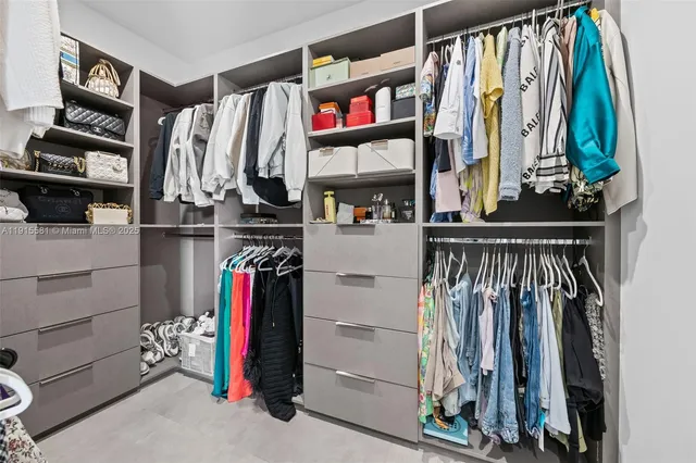 a view of walk in closet with clothes and shoes
