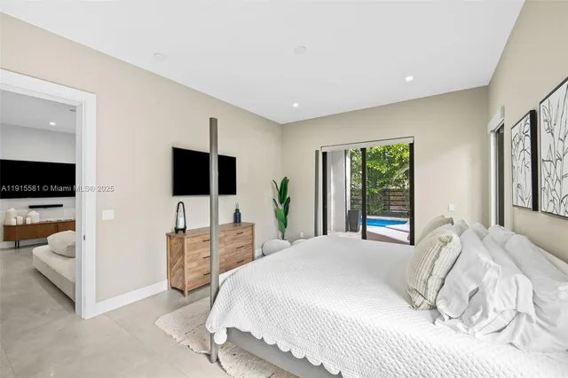 a large bedroom with a bed and flat tv screen on the dresser