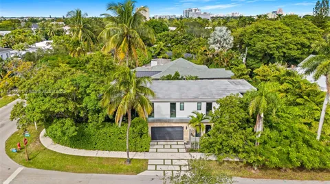 a view of a backyard with plants and large trees