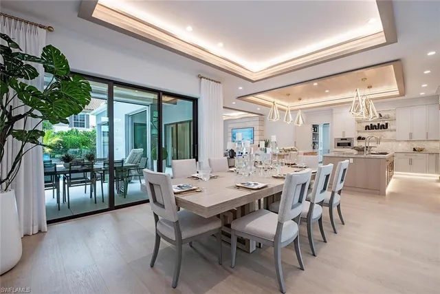 a dining room with furniture a potted plant and a large window