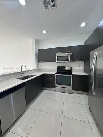 a kitchen with stainless steel appliances a stove a sink and a refrigerator