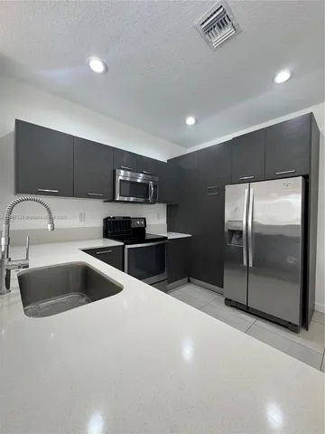 a kitchen with stainless steel appliances granite countertop a sink and a refrigerator