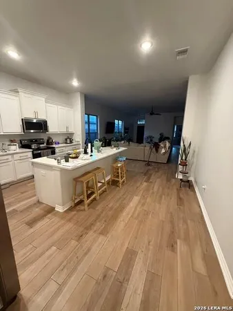 a living room with stainless steel appliances furniture a kitchen view wooden floor and a view of kitchen