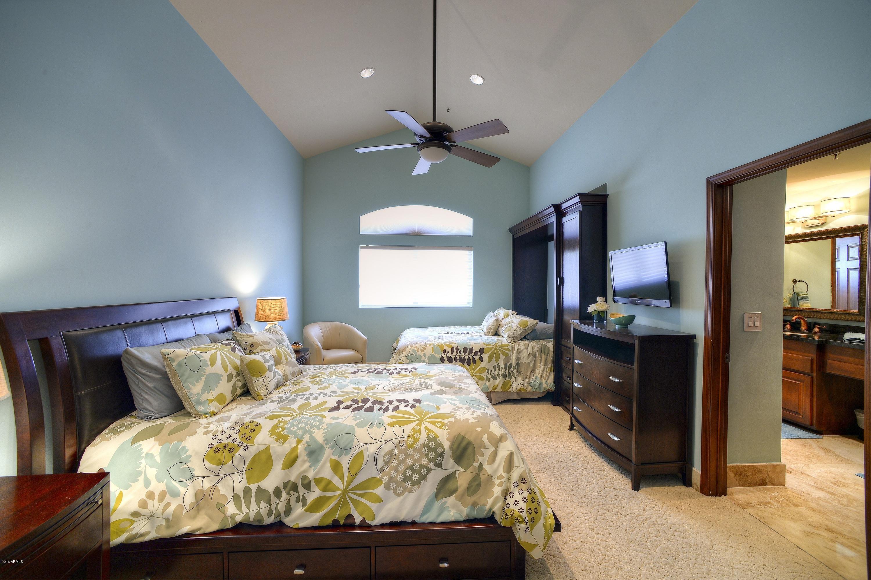 7740 East Gainey Ranch Road, Unit 58 Scottsdale, AZ 85258 - Photo 15 of 27 a bedroom with a bed and a chandelier