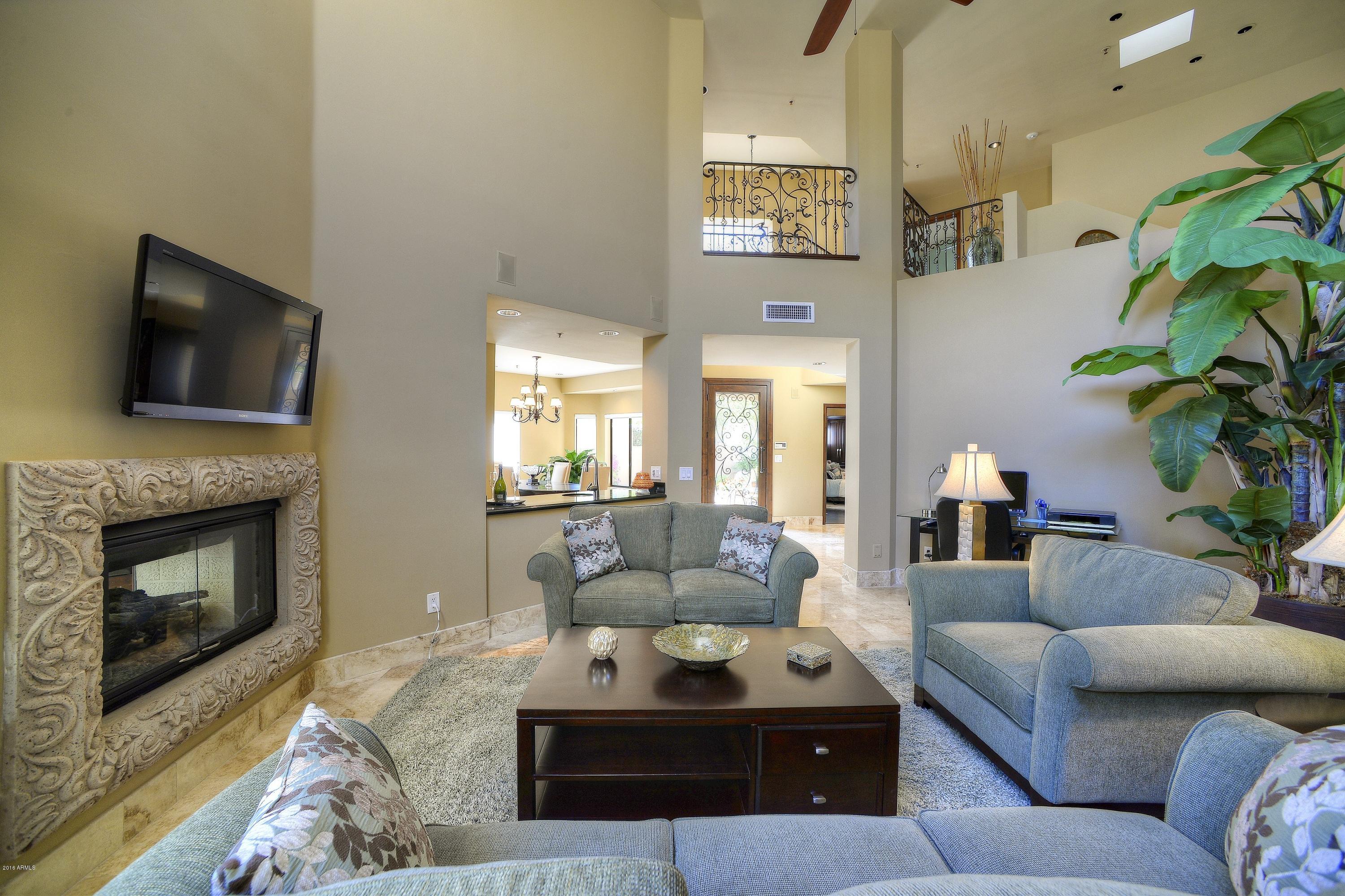 7740 East Gainey Ranch Road, Unit 58 Scottsdale, AZ 85258 - Photo 3 of 27 a living room with furniture a fireplace and a flat screen tv